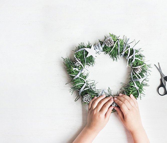 Grüner Kranz mit Schere und zwei Hände